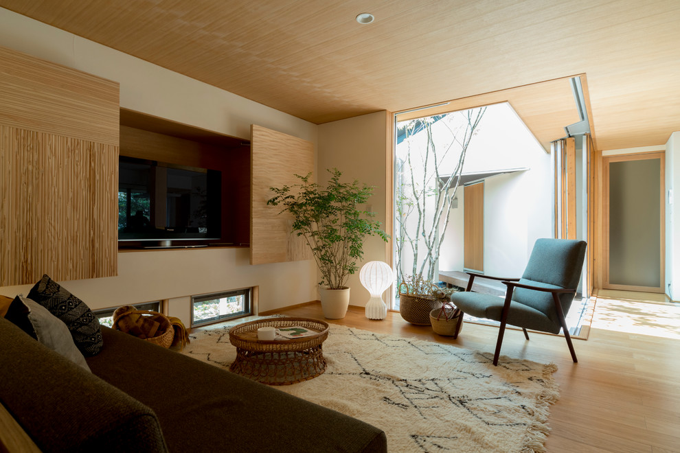 Cette photo montre un salon moderne avec un mur beige, parquet clair, aucune cheminée et un téléviseur fixé au mur.