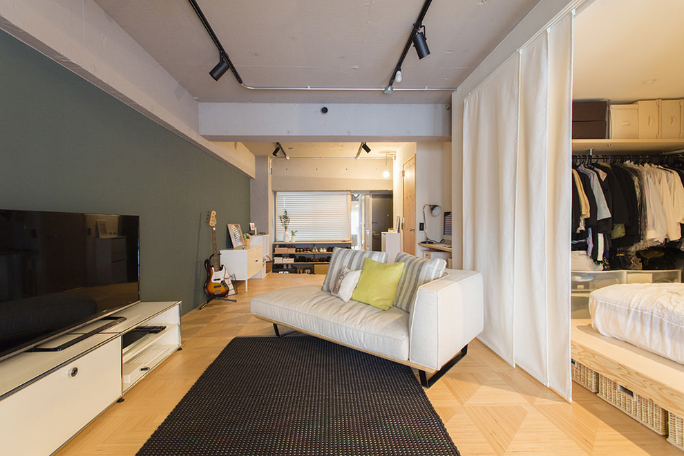 Imagen de salón abierto urbano con paredes multicolor, suelo de madera clara, televisor independiente y suelo beige
