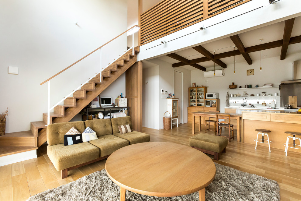 Источник вдохновения для домашнего уюта: открытая гостиная комната в скандинавском стиле с белыми стенами, светлым паркетным полом и коричневым диваном