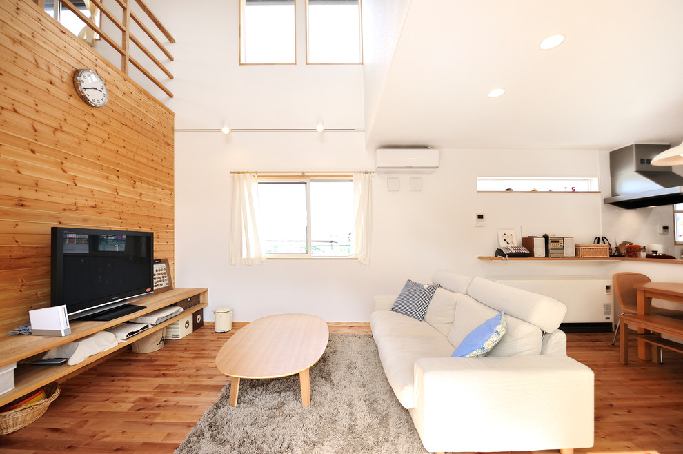 Offenes Modernes Wohnzimmer ohne Kamin mit weißer Wandfarbe, hellem Holzboden und freistehendem TV in Sonstige