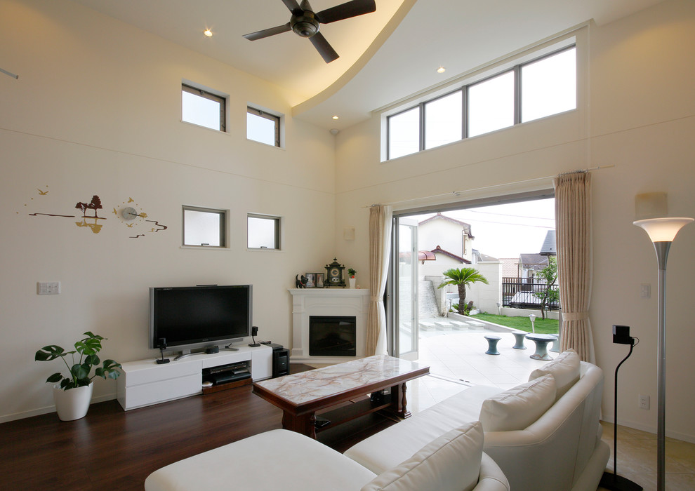 Modern inredning av ett allrum med öppen planlösning, med vita väggar, mörkt trägolv, en fristående TV och brunt golv