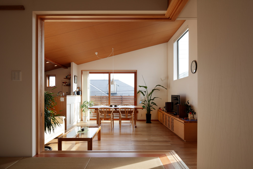 Ispirazione per un soggiorno design aperto con pareti bianche, pavimento in legno massello medio, TV autoportante e pavimento marrone