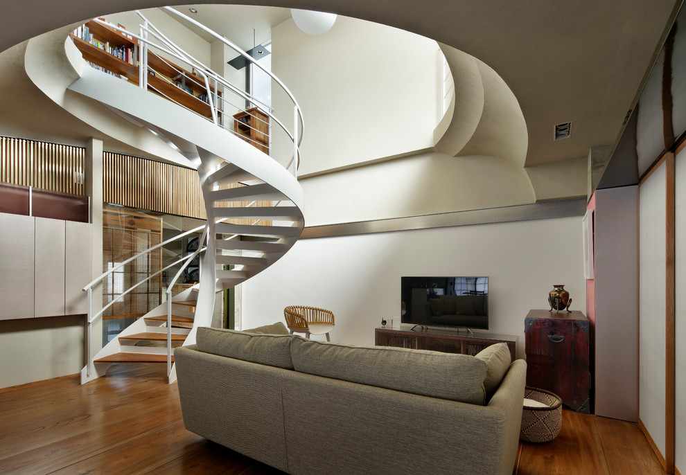 Immagine di un soggiorno design di medie dimensioni e aperto con pareti bianche, pavimento in legno massello medio, TV autoportante e pavimento marrone