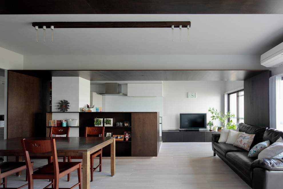 Modelo de salón abierto moderno con paredes blancas, suelo de contrachapado, televisor independiente y suelo beige