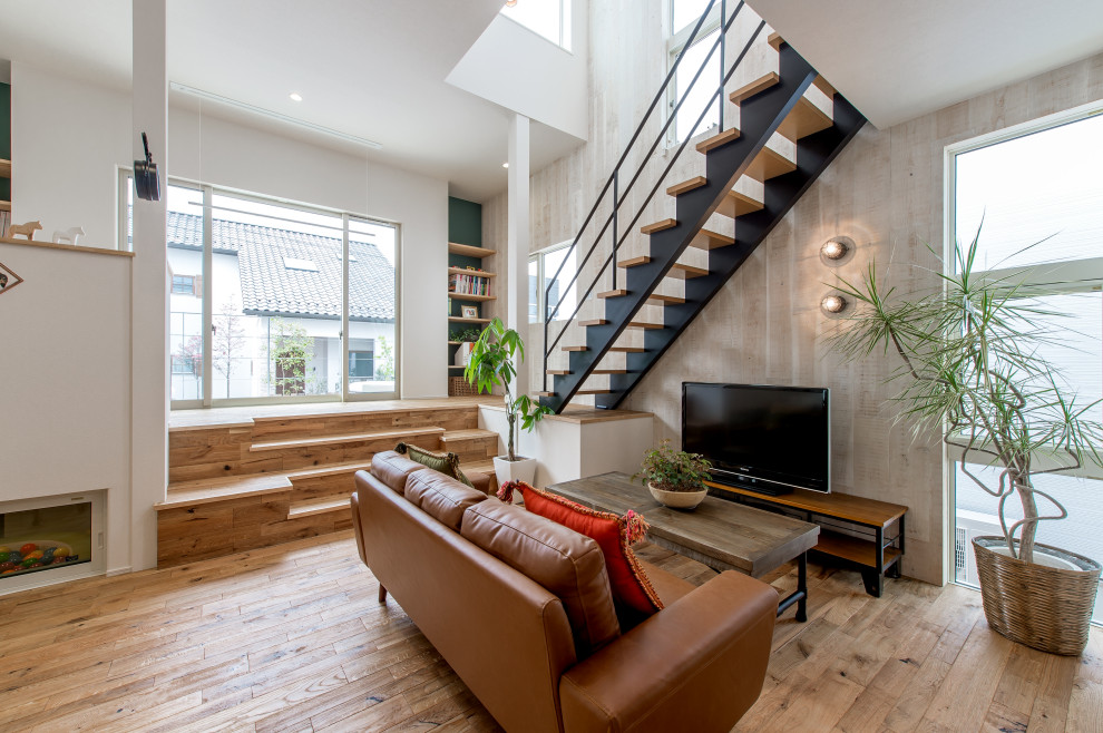 Idee per un soggiorno etnico aperto con pavimento in legno massello medio, carta da parati, pareti grigie, TV autoportante e pavimento marrone