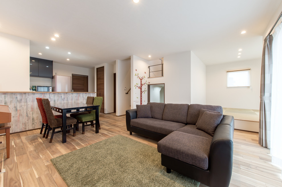 Mittelgroßes, Offenes Wohnzimmer mit braunem Holzboden, Tapetendecke und Tapetenwänden in Sonstige