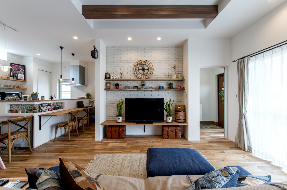 Mittelgroßes, Offenes Wohnzimmer mit braunem Holzboden, Tapetendecke und Ziegelwänden in Sonstige