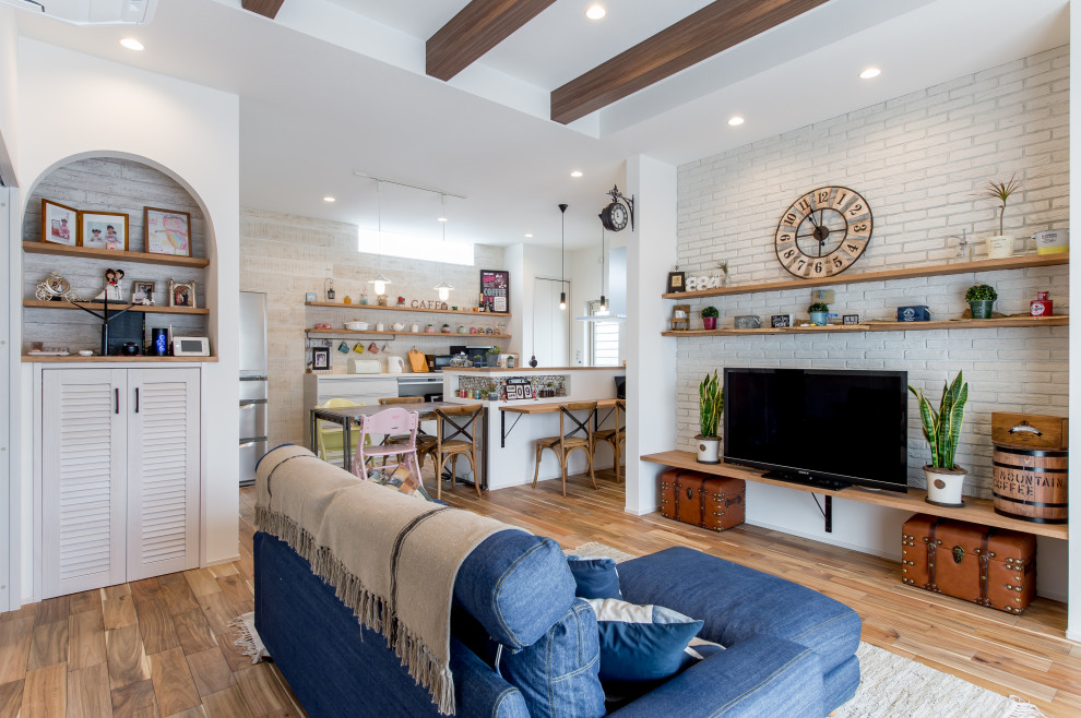 Mittelgroßes, Offenes Wohnzimmer mit braunem Holzboden, Tapetendecke und Ziegelwänden in Sonstige