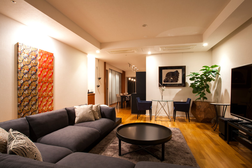 Photo of a world-inspired open plan living room in Tokyo with white walls, medium hardwood flooring, a freestanding tv and orange floors.