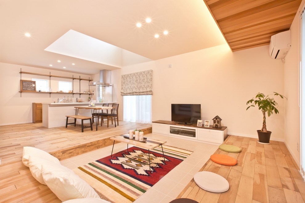 Immagine di un soggiorno etnico con pareti bianche, pavimento in legno massello medio e TV autoportante