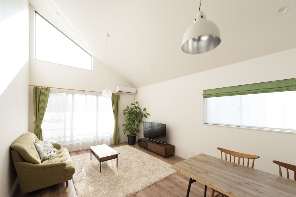 World-inspired living room in Osaka with white walls, medium hardwood flooring, a freestanding tv and brown floors.