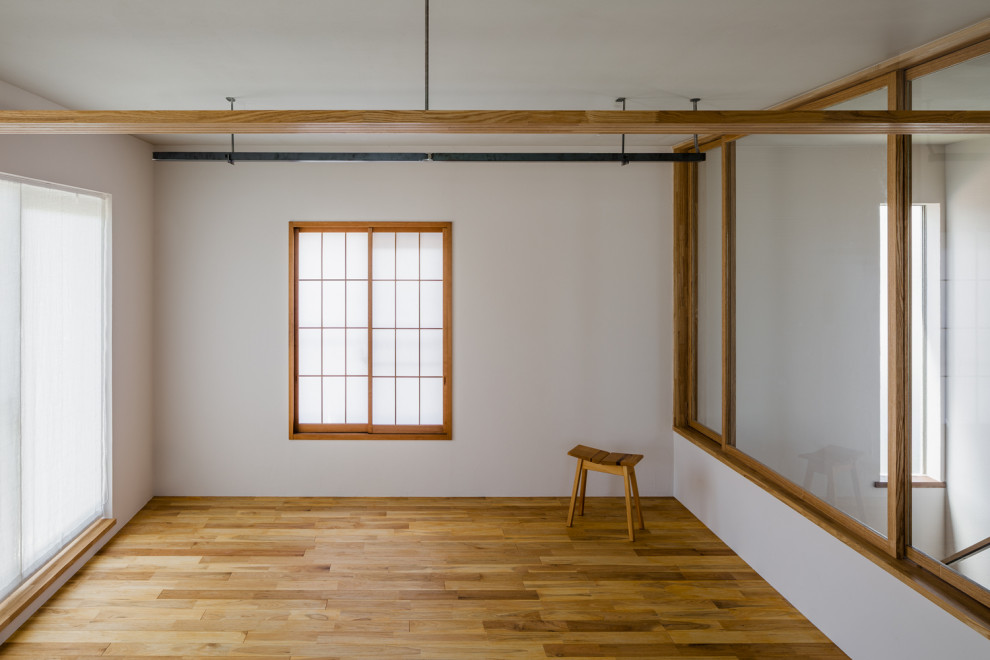 Asiatisk inredning av ett litet allrum med öppen planlösning, med vita väggar, mellanmörkt trägolv och brunt golv