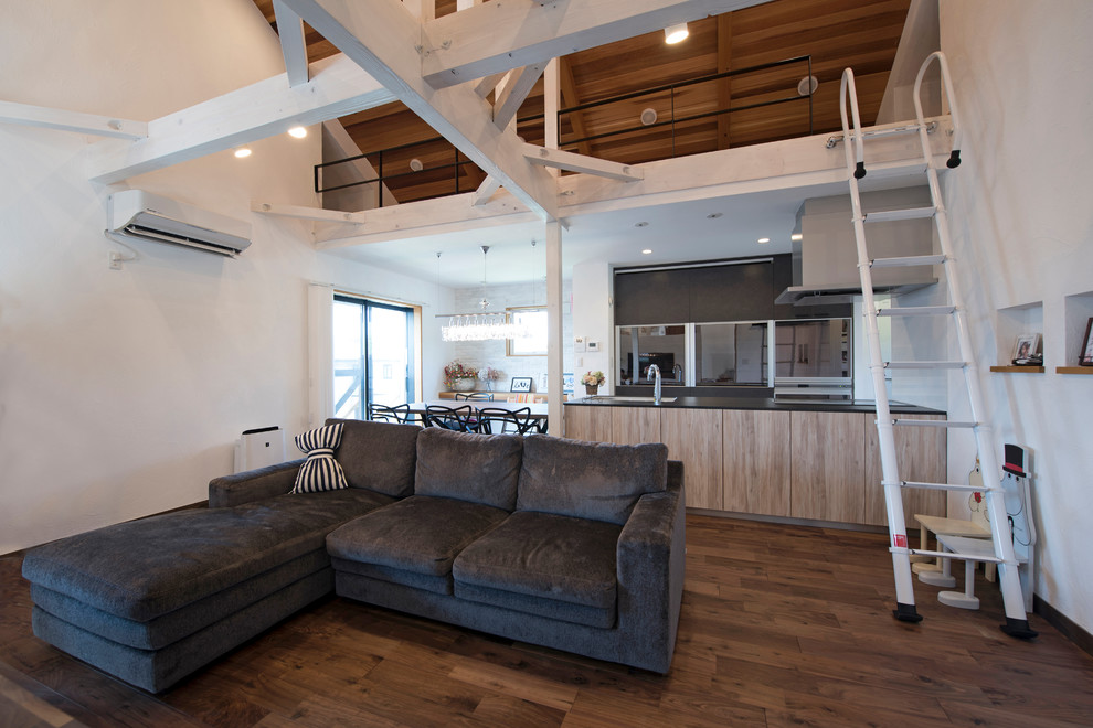 Offenes Modernes Wohnzimmer mit weißer Wandfarbe, dunklem Holzboden und braunem Boden in Sonstige