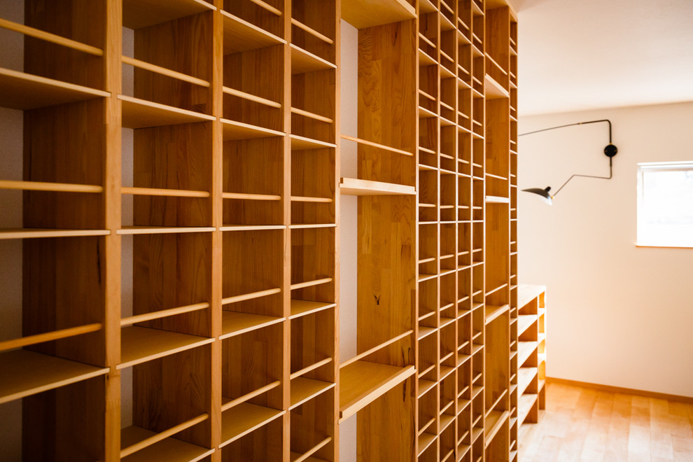 Diseño de biblioteca en casa abierta moderna sin chimenea con paredes blancas, suelo de madera en tonos medios, televisor colgado en la pared y suelo beige