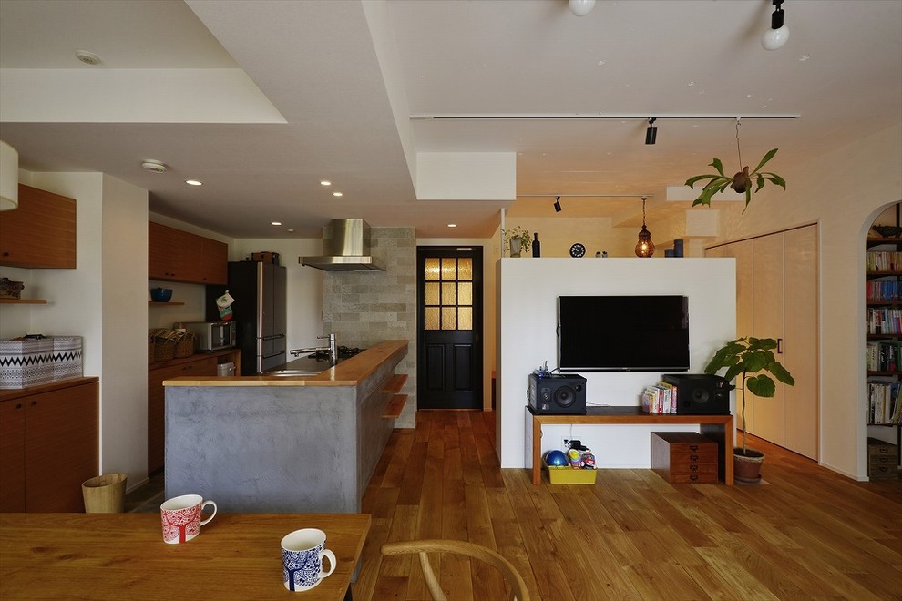 Ejemplo de salón abierto actual de tamaño medio con paredes blancas, suelo de madera en tonos medios, televisor colgado en la pared y suelo marrón