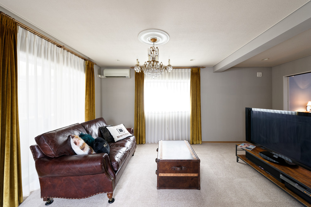 Eklektisk inredning av ett vardagsrum, med grå väggar, en fristående TV och grått golv