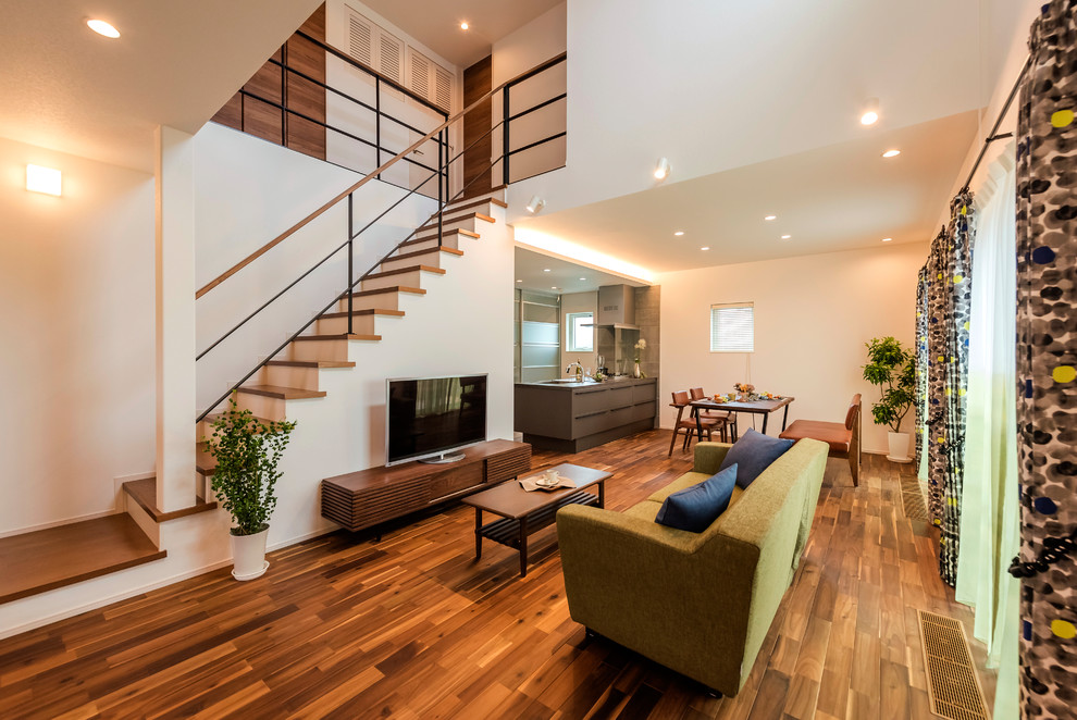 Imagen de salón abierto moderno con paredes blancas, suelo de madera oscura, televisor independiente y suelo marrón