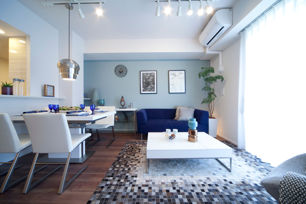 Стильный дизайн: открытая гостиная комната в современном стиле с паркетным полом среднего тона, белыми стенами и синим диваном без камина - последний тренд