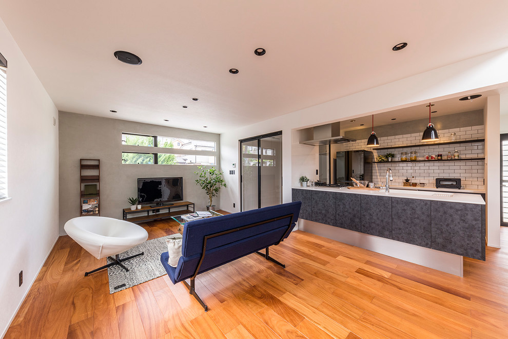 Foto de salón abierto actual con paredes blancas, suelo de madera en tonos medios, televisor independiente y suelo marrón