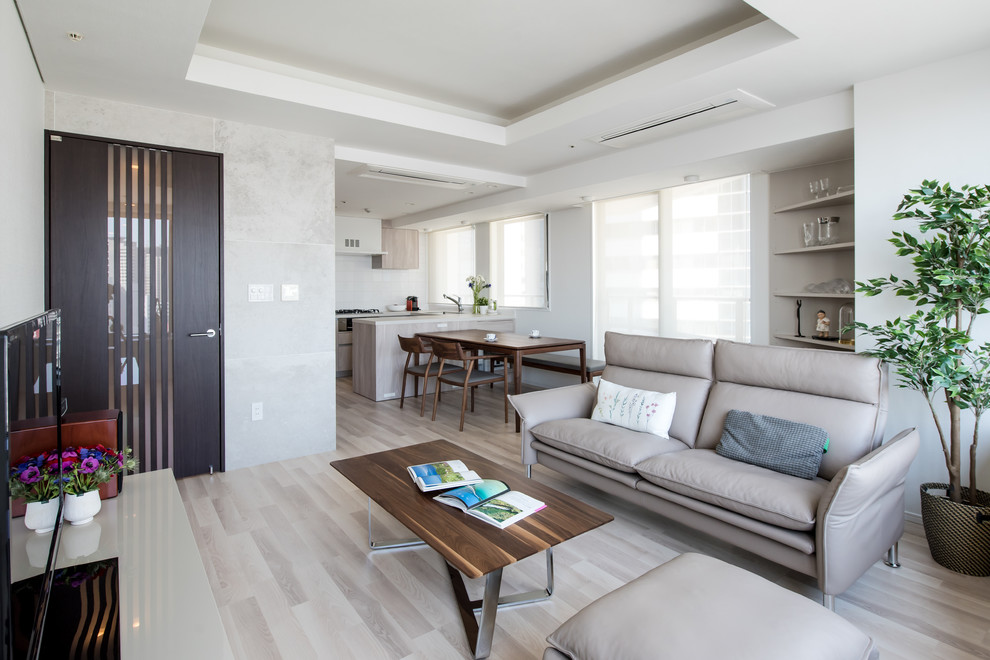Photo of a modern open plan living room in Tokyo with white walls, a freestanding tv and grey floors.