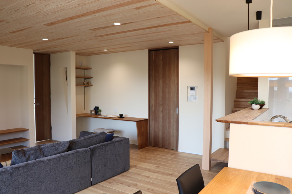 Idee per un soggiorno etnico di medie dimensioni e aperto con pareti beige, pavimento in legno massello medio, TV a parete e pavimento beige