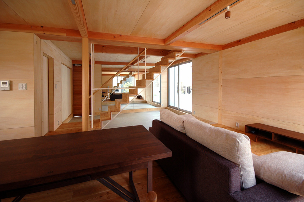 Ejemplo de salón para visitas abierto moderno pequeño con paredes marrones, suelo de madera clara y televisor independiente