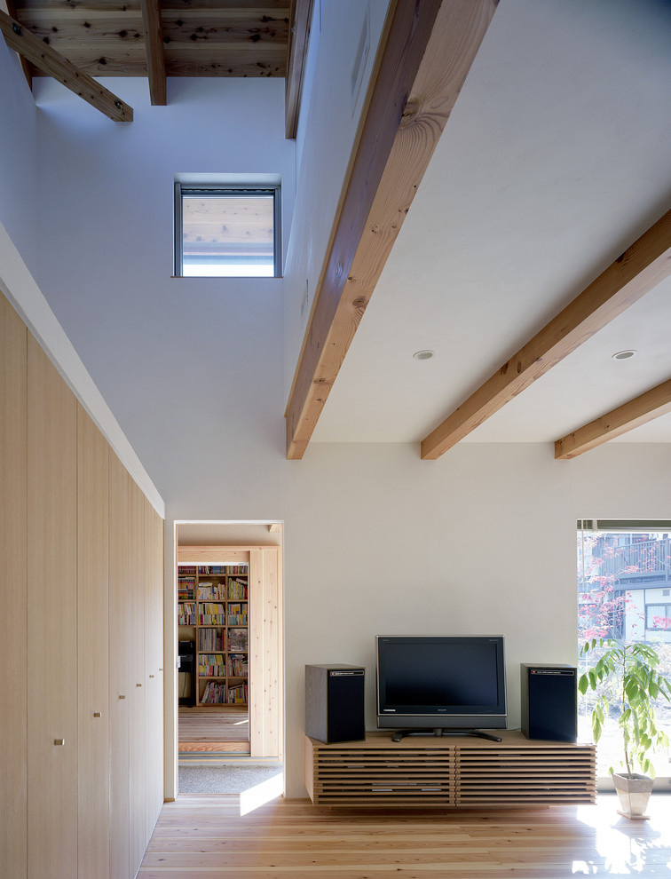 Пример оригинального дизайна: маленькая открытая гостиная комната в восточном стиле с белыми стенами, светлым паркетным полом, отдельно стоящим телевизором и коричневым полом для на участке и в саду