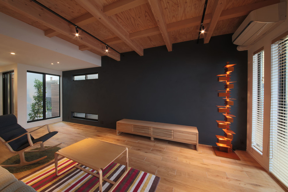 Exemple d'un petit salon moderne ouvert avec un sol en contreplaqué, aucune cheminée, un téléviseur indépendant, un mur noir et un sol marron.