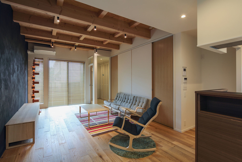 Пример оригинального дизайна: маленькая гостиная комната в стиле модернизм с черными стенами, паркетным полом среднего тона, отдельно стоящим телевизором и коричневым полом без камина для на участке и в саду