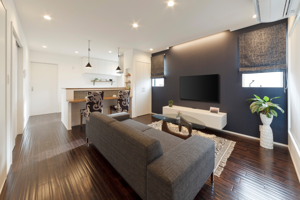 Offenes Wohnzimmer mit blauer Wandfarbe, dunklem Holzboden, TV-Wand, braunem Boden, Holzdielendecke und Holzdielenwänden in Sonstige