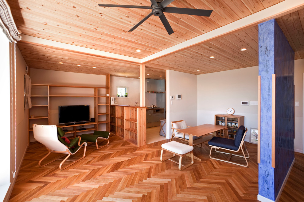 Example of a medium tone wood floor and brown floor living room design in Other with white walls and a tv stand