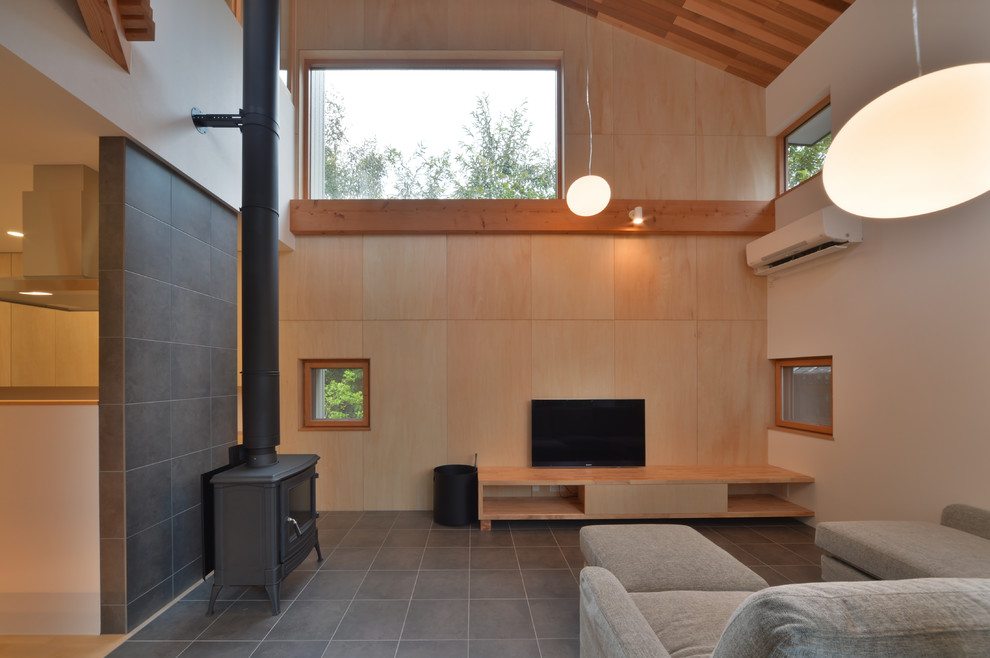 Immagine di un soggiorno etnico aperto con stufa a legna, pareti marroni, TV autoportante e pavimento grigio