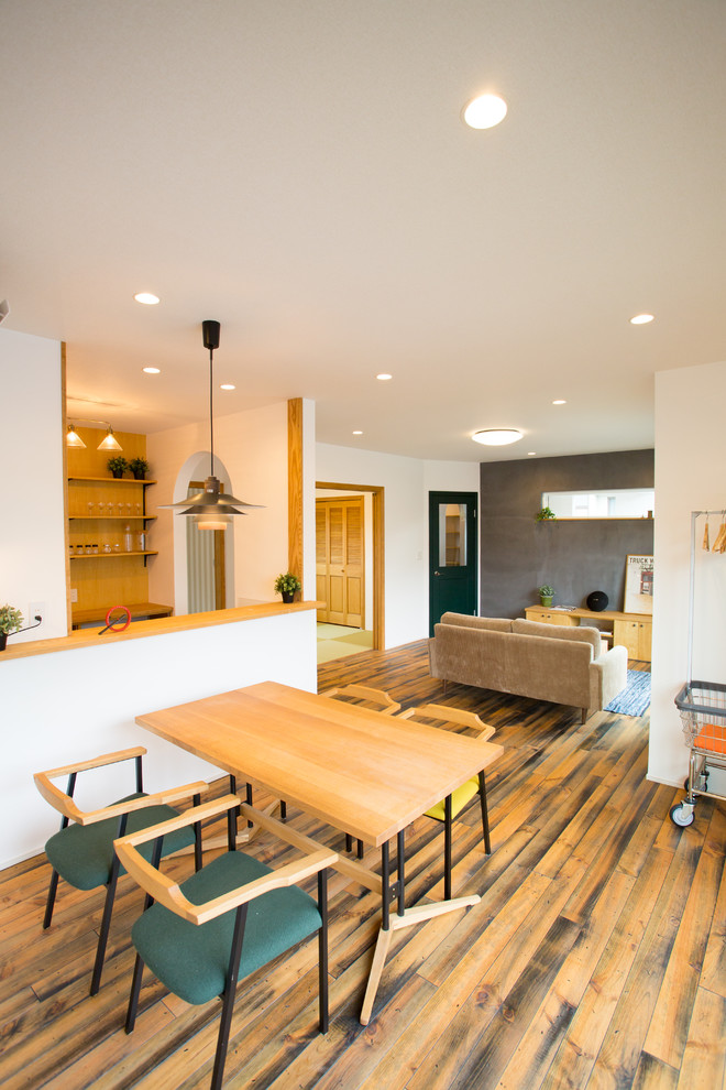 Idées déco pour un salon ouvert avec un mur multicolore, parquet foncé et un sol marron.