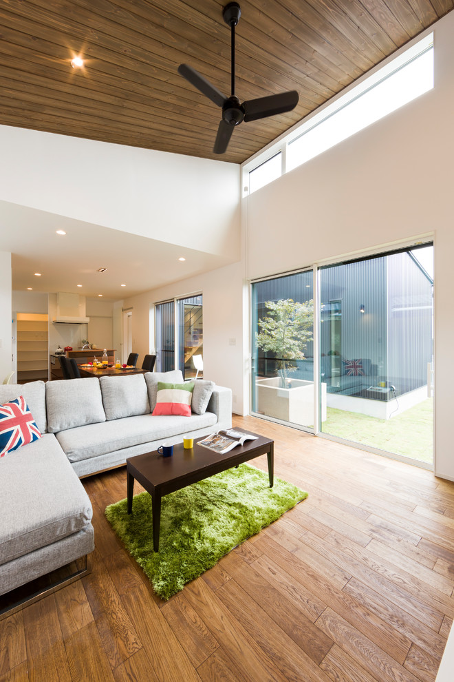 Immagine di un soggiorno contemporaneo aperto con pareti bianche, pavimento in legno massello medio e pavimento marrone