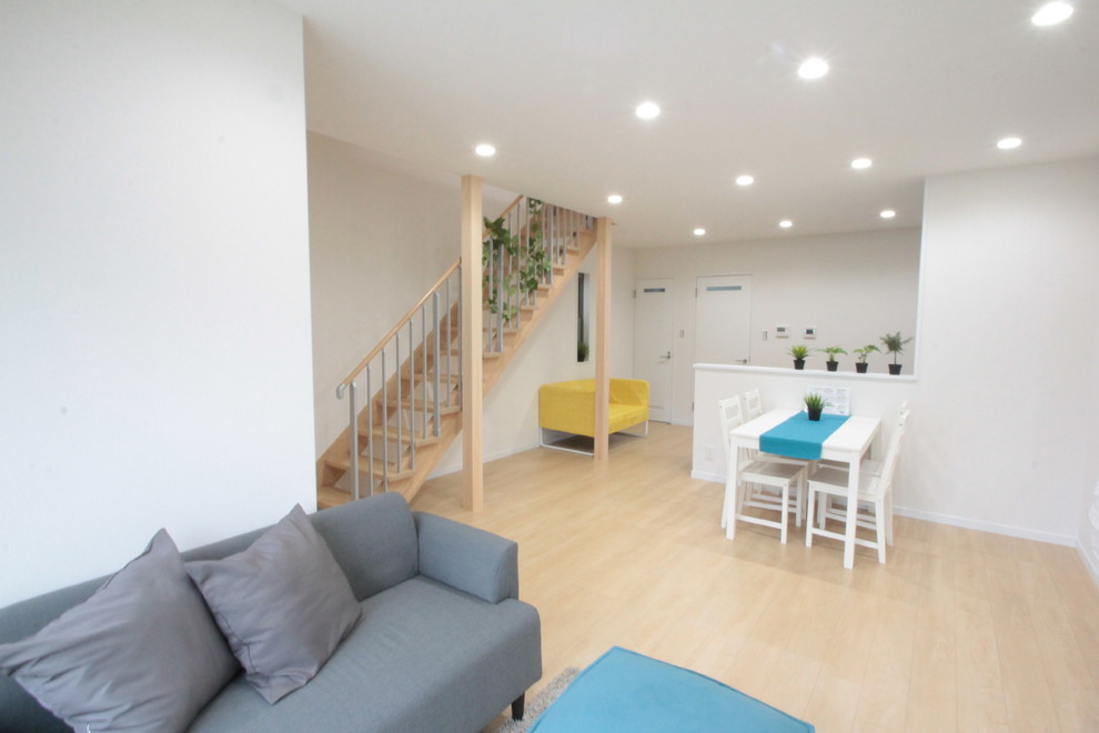 Offenes Uriges Wohnzimmer mit weißer Wandfarbe, Sperrholzboden und beigem Boden in Sonstige