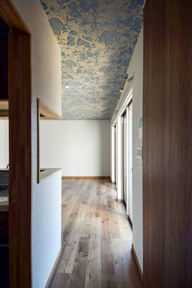 Immagine di un soggiorno minimalista di medie dimensioni e aperto con pareti bianche, pavimento in legno massello medio, nessun camino e pavimento beige