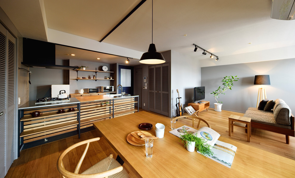 Aménagement d'un salon industriel ouvert avec un mur gris, un sol en bois brun, un téléviseur indépendant et un sol marron.