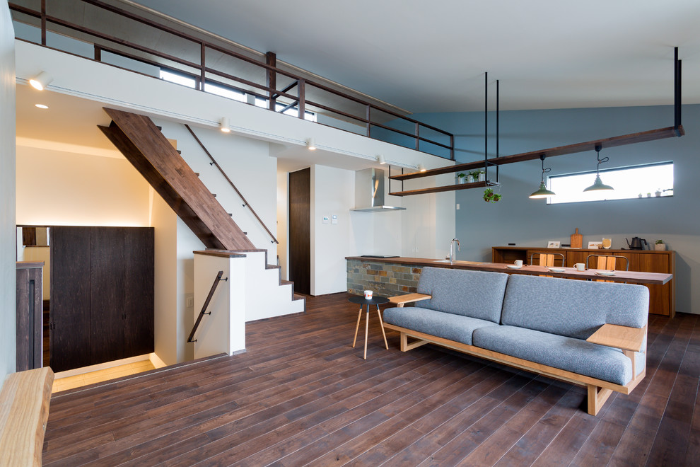 Идея дизайна: открытая гостиная комната в восточном стиле с синими стенами, темным паркетным полом и коричневым полом