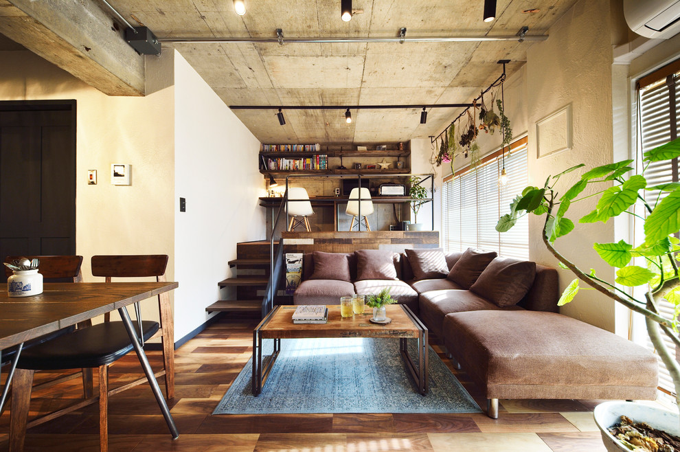 Diseño de salón abierto urbano con paredes blancas, televisor independiente y suelo marrón