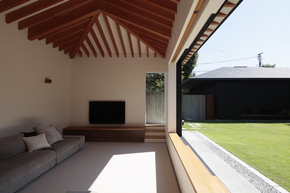 Modernes Wohnzimmer mit weißer Wandfarbe, freistehendem TV und grauem Boden in Sonstige