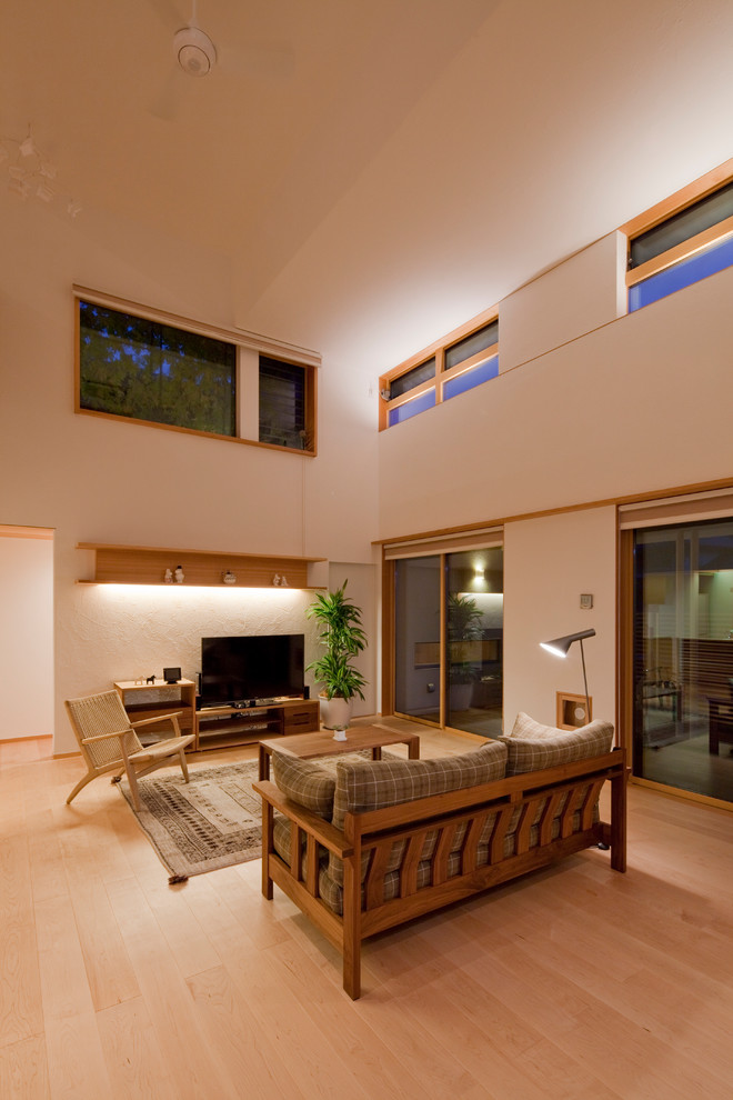 На фото: большая открытая гостиная комната в скандинавском стиле с белыми стенами, светлым паркетным полом, отдельно стоящим телевизором и коричневым полом