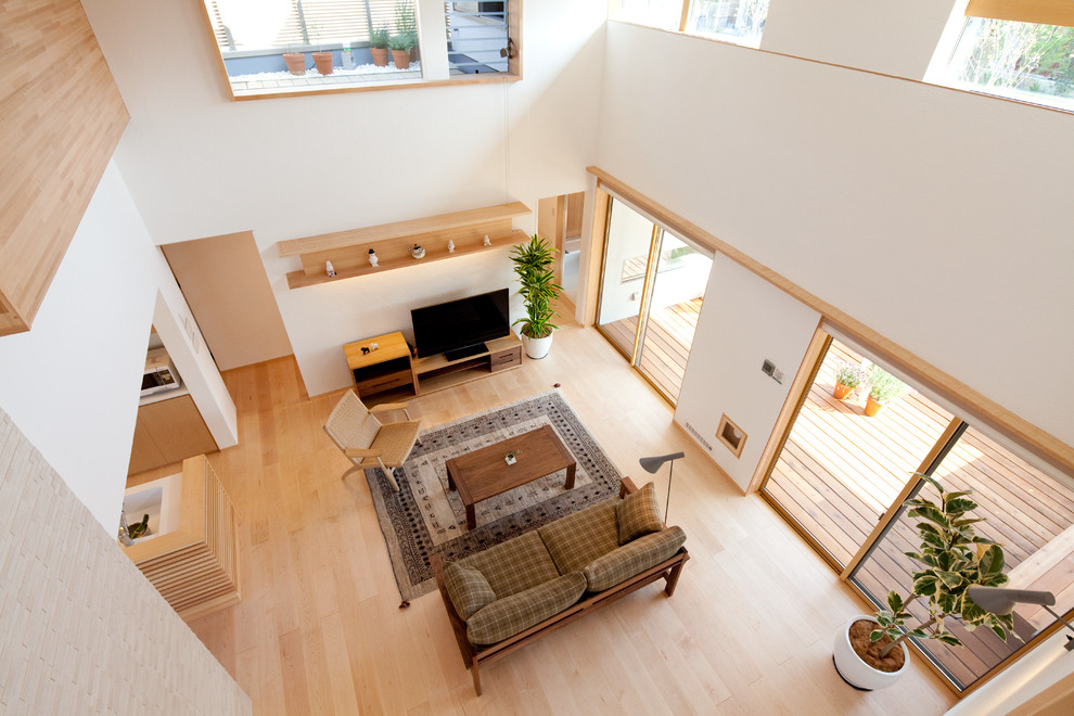 Imagen de salón abierto escandinavo grande con paredes blancas, suelo de madera clara y televisor independiente