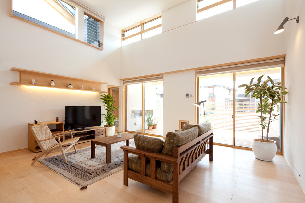 Großes, Offenes Skandinavisches Wohnzimmer mit weißer Wandfarbe, hellem Holzboden, freistehendem TV und braunem Boden in Sonstige