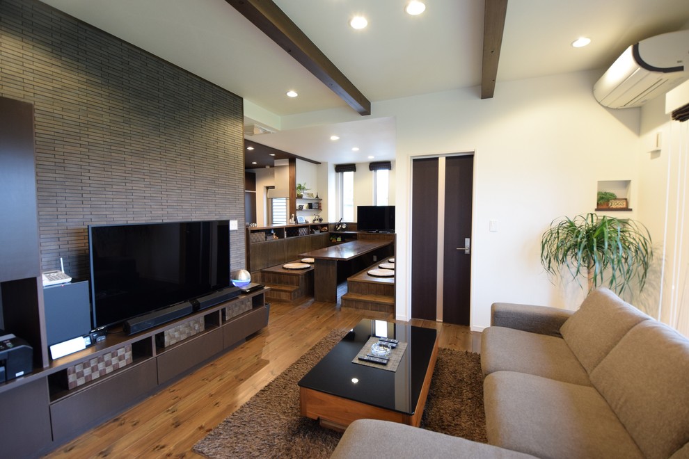 Offenes Modernes Wohnzimmer mit bunten Wänden, braunem Holzboden, freistehendem TV und braunem Boden in Sonstige
