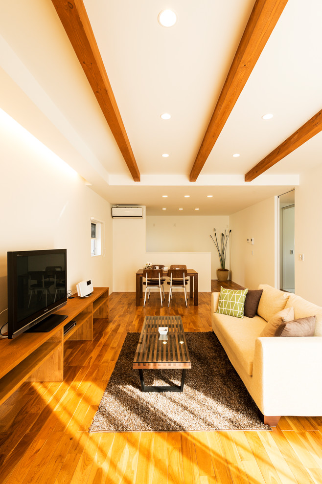 Esempio di un soggiorno etnico aperto con pareti bianche, pavimento in legno massello medio, TV autoportante e pavimento marrone