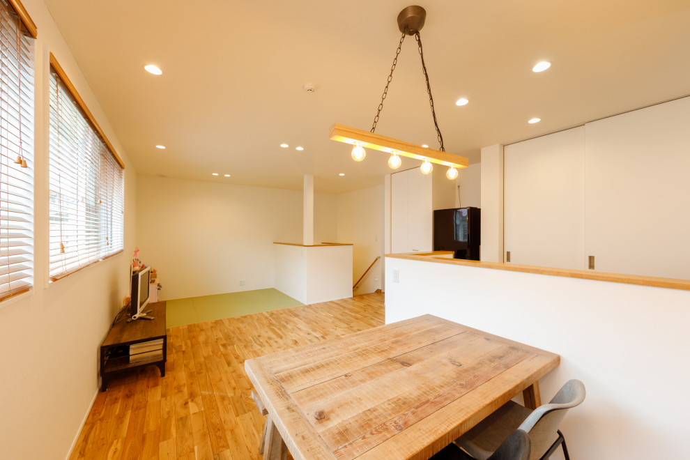 Bild på ett litet minimalistiskt allrum med öppen planlösning, med vita väggar, mellanmörkt trägolv, brunt golv, ett finrum och en fristående TV