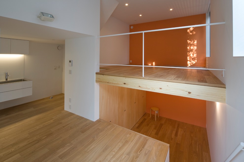 Exempel på ett litet modernt loftrum, med ett finrum, orange väggar, plywoodgolv och brunt golv