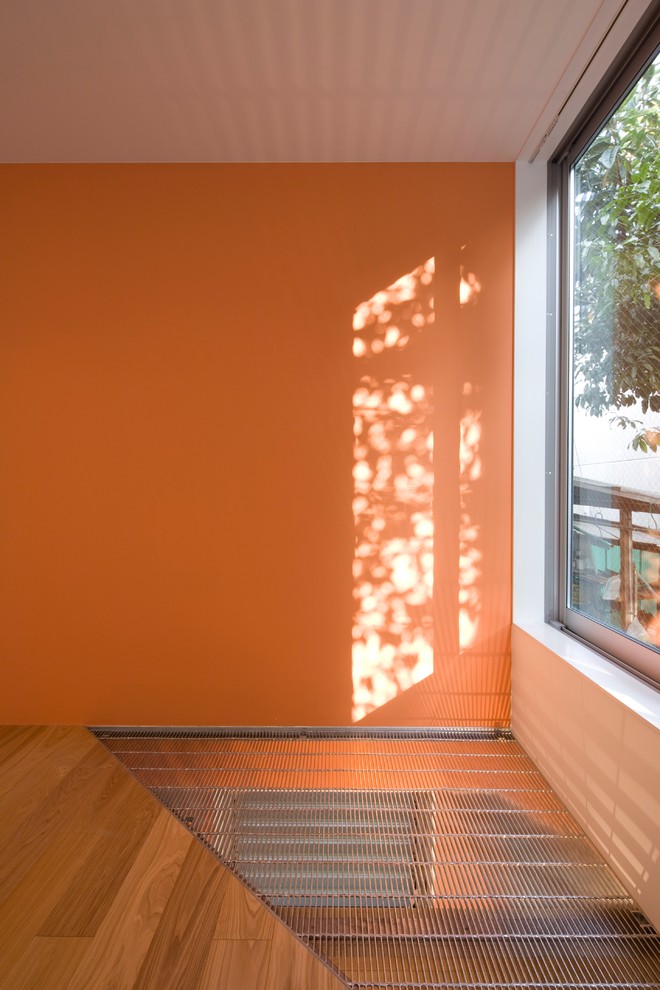 Exemple d'un petit salon mansardé ou avec mezzanine moderne avec une salle de réception, un mur orange, un sol en contreplaqué, aucune cheminée et un sol marron.