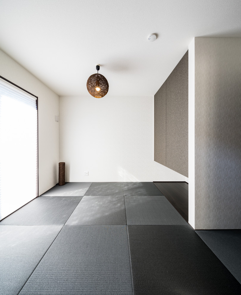 Photo of a modern living room in Nagoya with white walls, tatami flooring, a freestanding tv and black floors.