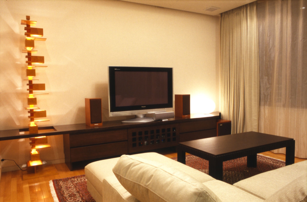 Diseño de salón abierto asiático con paredes beige, suelo de contrachapado, televisor independiente y suelo marrón